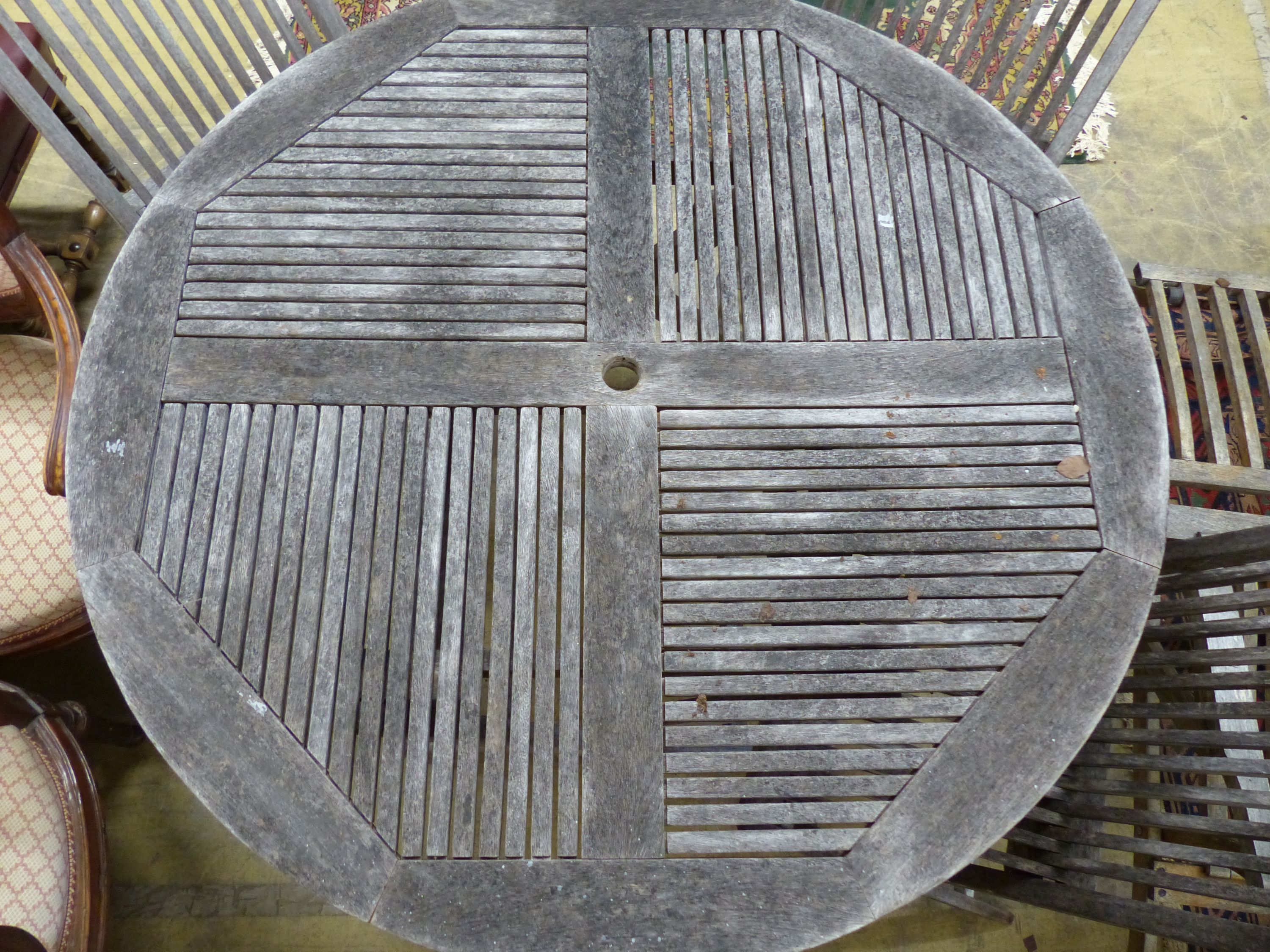 A teak garden table, 125cm diameter and four matching chairs, all folding